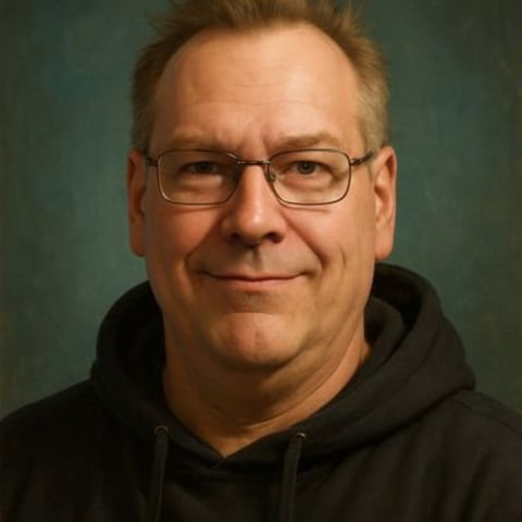 Middle-aged man wearing glasses and a black hoodie, smiling at the camera against a green background